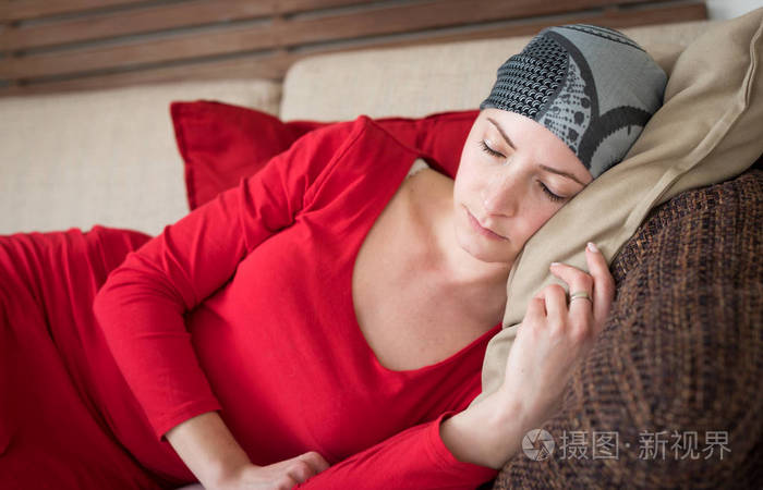 年轻的成年女性癌症患者在沙发上放松.疲惫,疲惫,抑郁的癌症患者