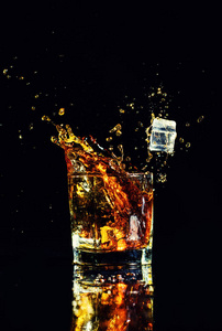 黑色背景飞溅的威士忌, 在玻璃杯白兰地的孤立拍摄