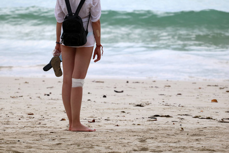 受伤的旅游女孩在海滩上放松