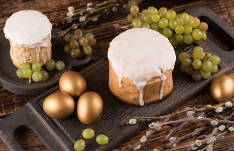 复活节蛋糕和五颜六色的彩蛋在节日复活节餐桌上。金黄蛋和传统复活节蛋糕在木背景