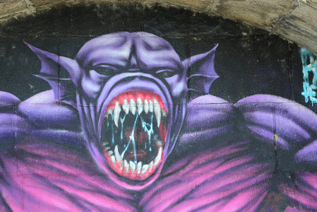 涂鸦画碎片。在街头艺术文化的风格上装饰着漆渍的旧墙。紫色可怕的怪物