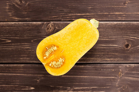 光滑梨形橙巴特纳特南瓜 flatlay 在棕木上的一个半照片