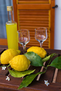 柠檬水或柠檬在一个玻璃瓶, 眼镜, 柠檬的树枝上, 叶子放在木桌上