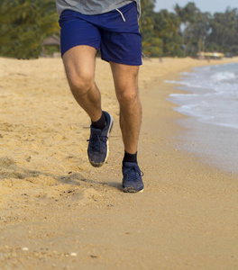 男子在海滩中运行。对角视图