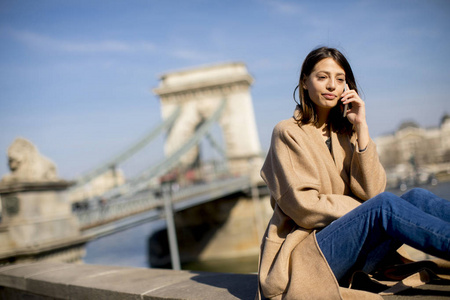 匈牙利布达佩斯的年轻女子使用带链桥的手机