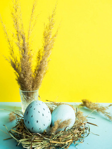 复活节彩蛋在一窝草。黄色背景
