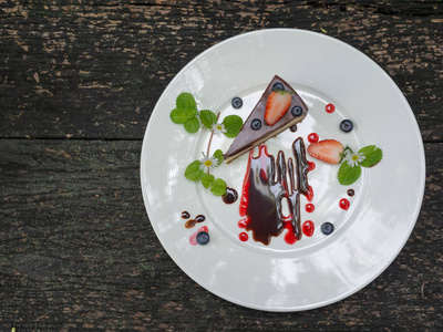 Choccolate 芝士蛋糕与草莓和蓝莓在板材上的木质背景顶部视图