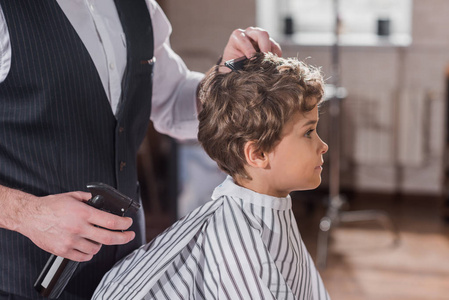 理发镜头的理发师梳头发的小孩在理发店