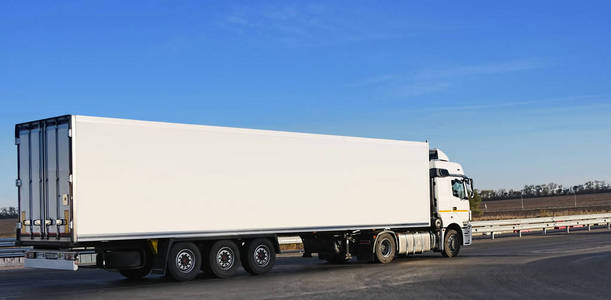 一辆白色拖车在柏油路上运送货物照片