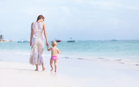 在沙滩上散步的小女儿和妈妈