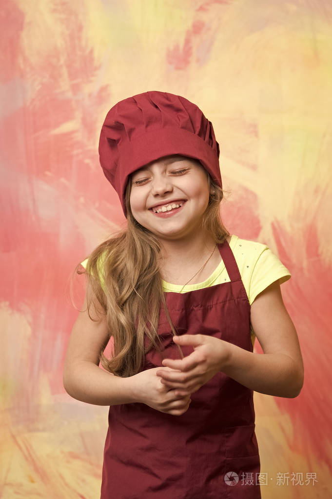 刚出生的快乐的女孩厨师笑在红色的厨师帽围裙