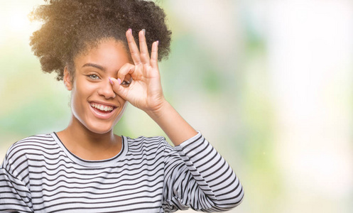 年轻的美国黑人妇女短信使用智能手机在孤立的背景与快乐的脸微笑做 ok 标志与手在眼睛看通过手指