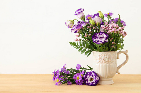 在木桌和白色背景的花瓶里的紫色花朵的夏天花束