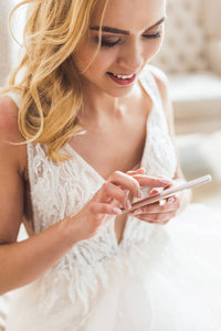 年轻新娘使用智能手机在婚礼沙龙