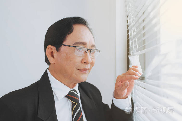 成熟的老板在办公室里沉思透过窗户思考和寻找