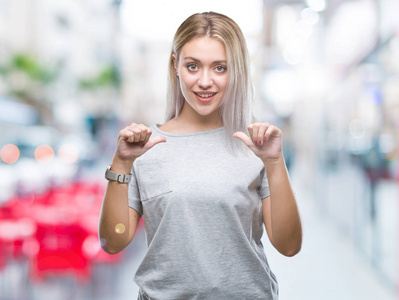 年轻的金发女人在孤立的背景下, 脸上露出自信的笑容, 用手指自豪和快乐地指着自己。