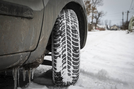 汽车轮胎在冬天的路上布满了积雪。车在下雪的方式在早晨