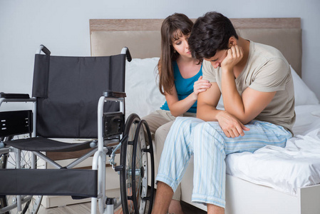绝望的男子在轮椅上与他的悲伤的妻子照片