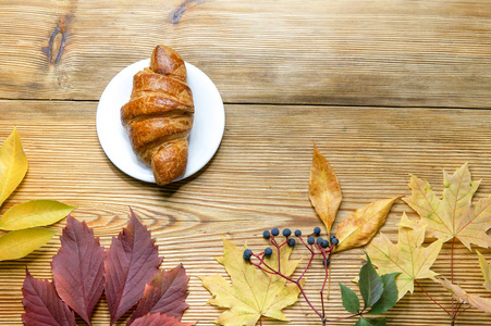 与法国羊角面包和秋叶在木制质朴的背景, 顶部视图的秋天早晨好