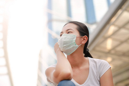 女人穿着防护口罩保护污染和流感坐在公共区域