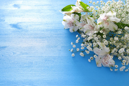 白色美丽的花朵排列在蓝色的木质背景上。复制空间