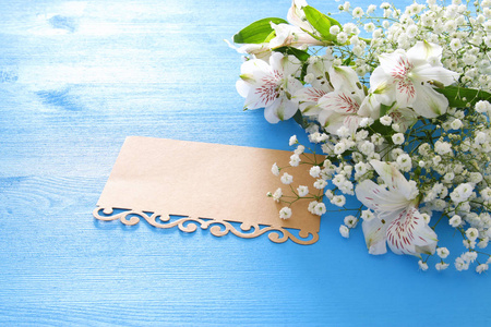 白色美丽的花朵排列和空字母在蓝色的木质背景的最高视图。复制空间