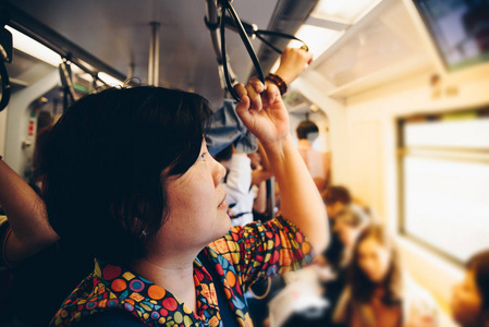 亚洲女子乘坐轻轨列车在城市