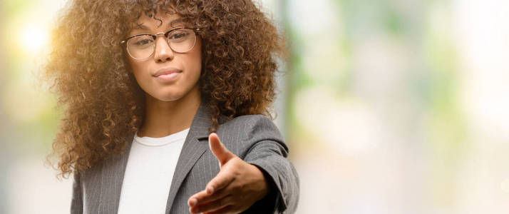 非洲裔美国商界妇女戴眼镜微笑友好提供握手作为问候和欢迎。成功的企业