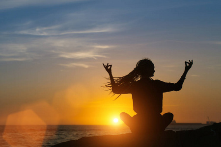 冥想瑜伽女人的剪影在海面上的日落
