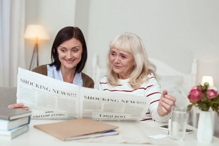 活跃的老年妇女和看护者阅读报纸
