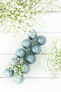 蓝色复活节彩蛋在满天星花束之间的白色桌上