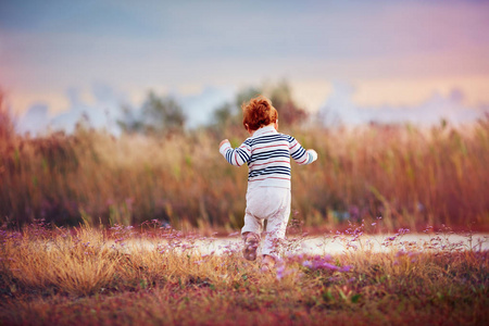 在夕阳下奔跑着盛开的夏日田野在干草堆上的小男孩和女孩在阳光下奔跑