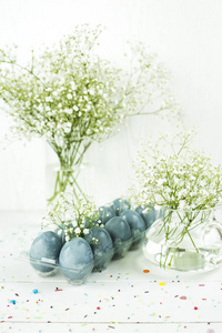 蓝色复活节彩蛋在满天星花束之间的白色桌上