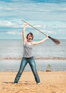 滑稽的女人，用扫帚在海滩上