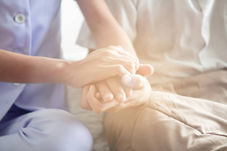安慰的手.年轻的护士握着老人的手.