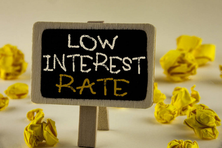 显示低利率的文本符号。概念照片管理金钱明智地支付较低的利率节省在木告示板上的纯背景黄色纸球