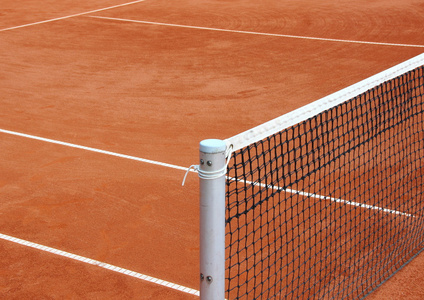 网球网在空的红色砂砾法院图片