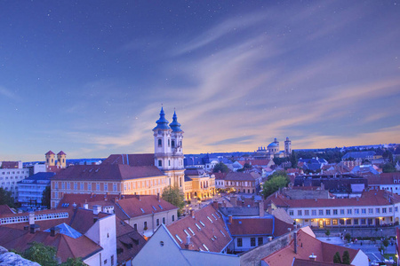 少数民族教堂的美丽的看法和 Eger, 匈牙利的城市全景, 在日落