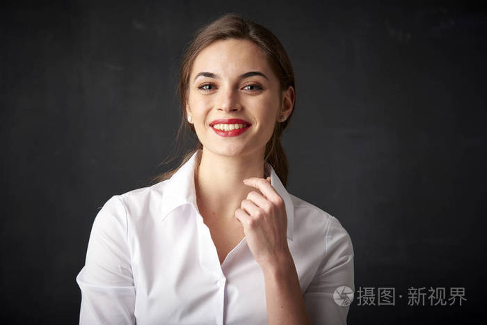特写肖像的自信andhappy年轻女子摆在黑暗的背景而看着相机