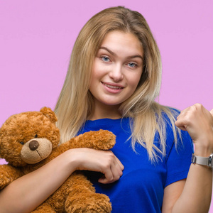 年轻的白种人妇女抱着可爱的泰迪熊在孤立的背景指向和显示与拇指面带笑脸微笑