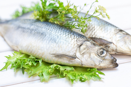 油性鲱鱼在一张白色的木桌上的盐渍的鲱鱼照片