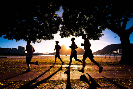 美丽的地平线四人的剪影在清晨在里约热内卢美丽的温暖的日出奔跑与