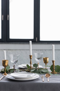 关闭与桉树, 老式的餐具, 蜡烛持有人蜡烛和空盘子的乡村餐桌设置的视图
