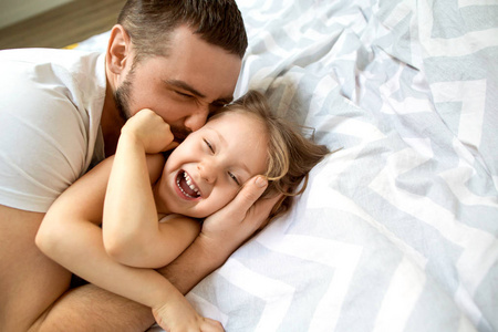 爸爸和女儿在家里的床上玩得很开心。