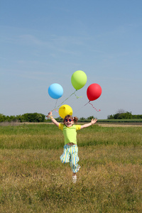 快乐的小女孩与气球跳跃的字段上