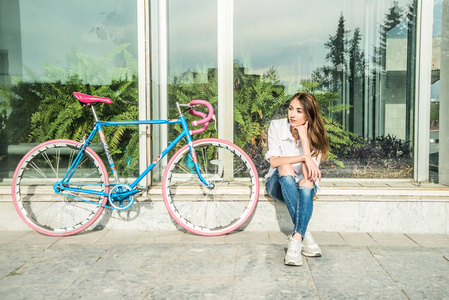 时尚时髦女孩坐在自行车靠窗附近