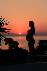 日落时分海滩上孕妇的剪影