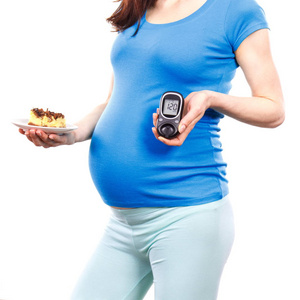 怀孕妇女持有血糖仪与测量糖水平和一块芝士蛋糕的坏结果