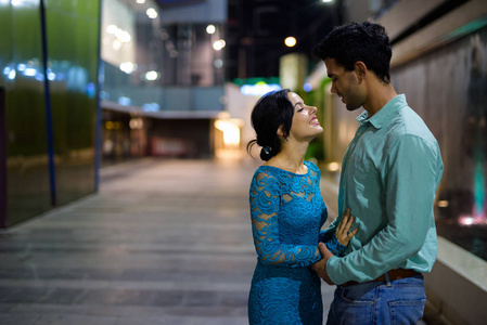 年轻的拉美裔夫妇探索城市街道在夜间一起