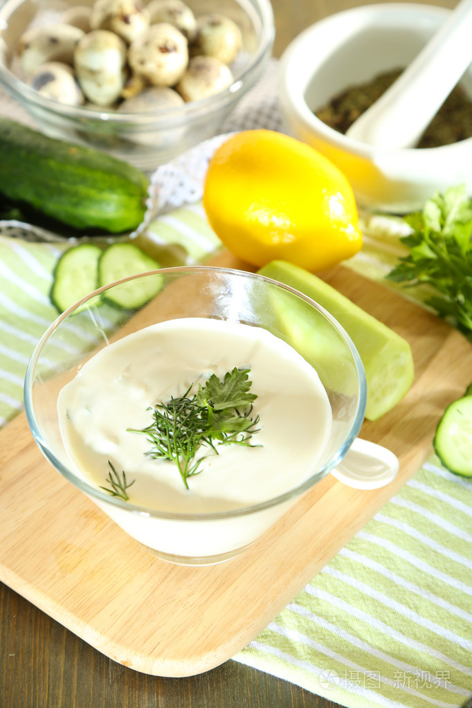 黄瓜酸奶在玻璃碗里,颜色餐巾,木制的背景上